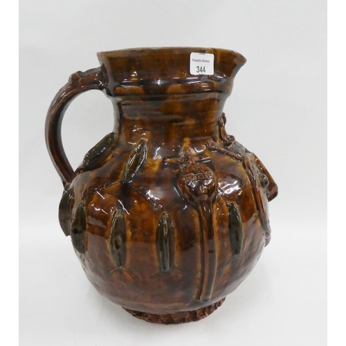 344 - Brown glazed pottery jug with moulded heart shape face and religious motifs throughout, apparently u... 