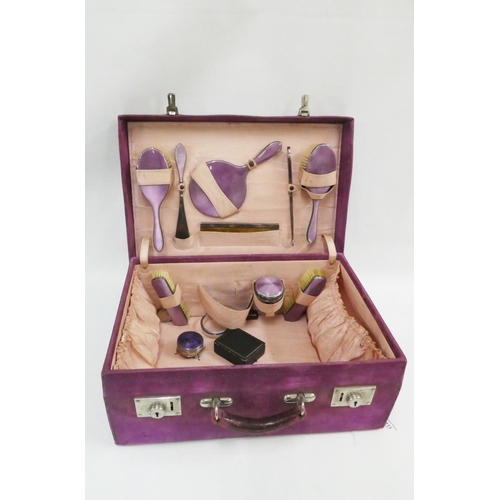 111 - Early 20th century purple suede vanity case containing a part suite of silver and enamel accessories... 