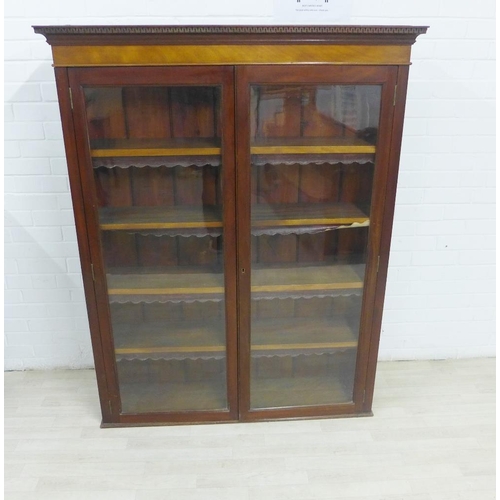 228 - Mahogany bookcase with dentil frieze and pair of glazed doors, with a shelved interior, 155 x 123cm