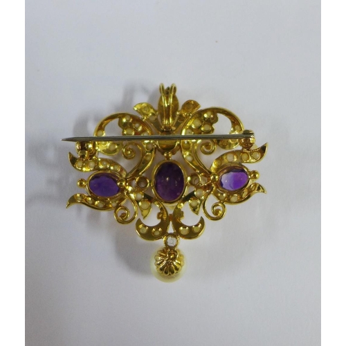 13 - Gold open work brooch / pendant, with a row of  three claw set amethysts, the central gemstone flank... 