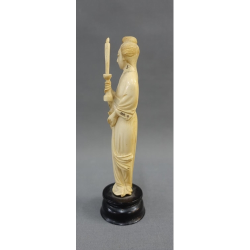 354 - Early 20th century ivory okimono of a woman, modelled standing with a candle, on a wooden plinth bas... 