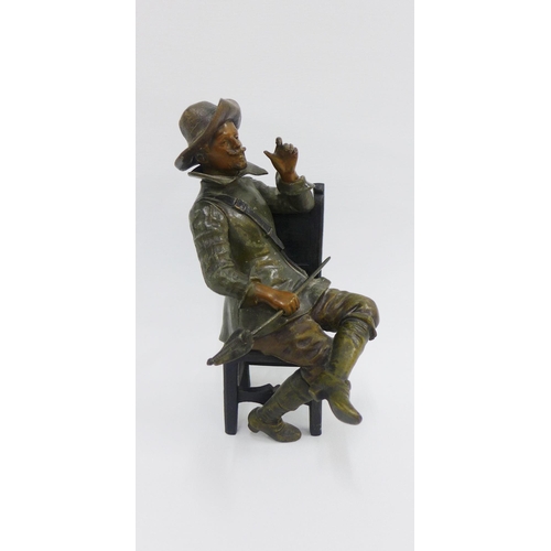 76 - Bronze patinated metal figure of a Cavalier, modelled seated on a high back chair, 26cm high