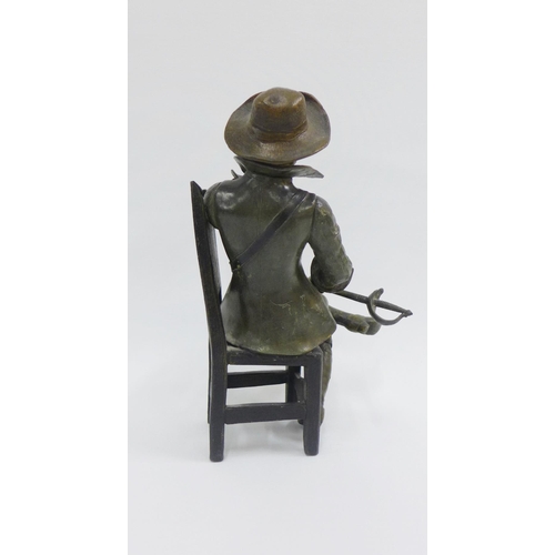76 - Bronze patinated metal figure of a Cavalier, modelled seated on a high back chair, 26cm high