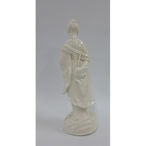 85 - Blanc de chine female figure, modelled standing carrying a basket of leaves, 26cm high