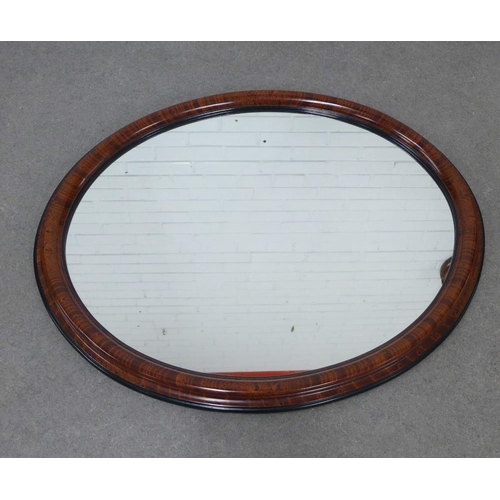 420 - A faux walnut and ebony framed mirror with an oval plate, 90 x 70cm