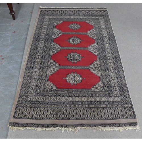 223 - Pakistan rug, red field with four central medallions within multiple geometric borders, 162 x 96cm