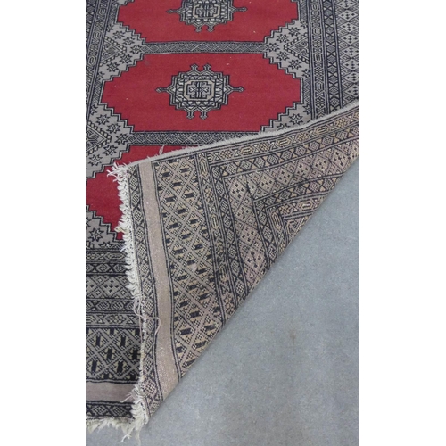 223 - Pakistan rug, red field with four central medallions within multiple geometric borders, 162 x 96cm