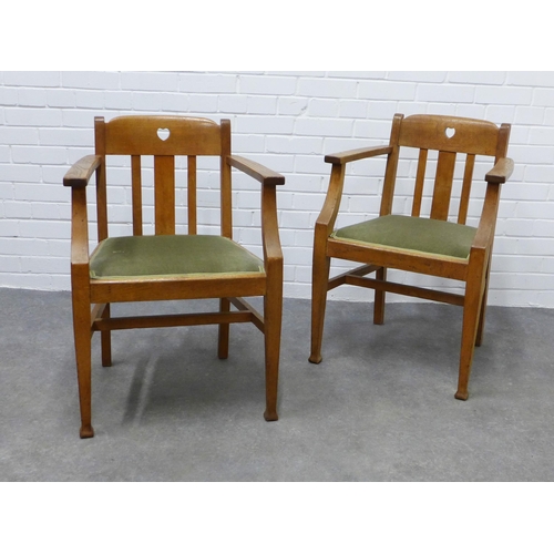 252 - A pair of Arts & Crafts oak open armchairs  in the manner of Liberty & Co, with pierced hearts to th... 