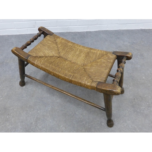 253 - An Arts & Crafts elm stool with a concave woven rush seat, 39 x 76 x 33cm.