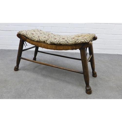 253 - An Arts & Crafts elm stool with a concave woven rush seat, 39 x 76 x 33cm.