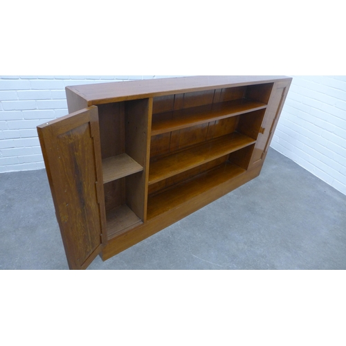 297 - An open bookcase, central shelves flanked by cupboard doors. 93 x 166 x 23cm.