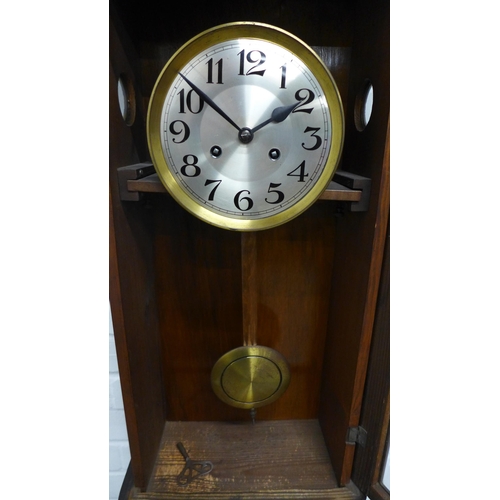 302 - Mahogany cased wall clock, silvered dial and arabic numerals, complete with pendulum . 74 x 33 x 18c... 