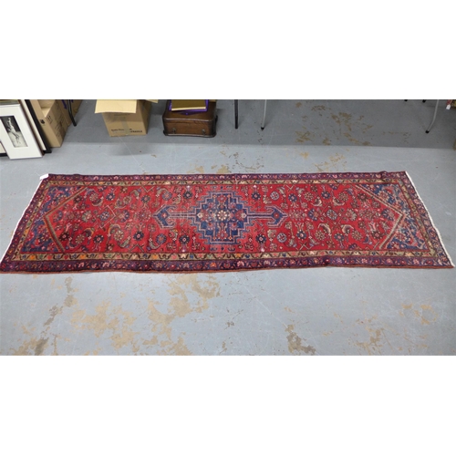 315 - North West Persian runner, red field with a pole medallion and flowerhead borders, 306 x 87cm