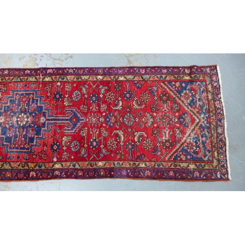 315 - North West Persian runner, red field with a pole medallion and flowerhead borders, 306 x 87cm