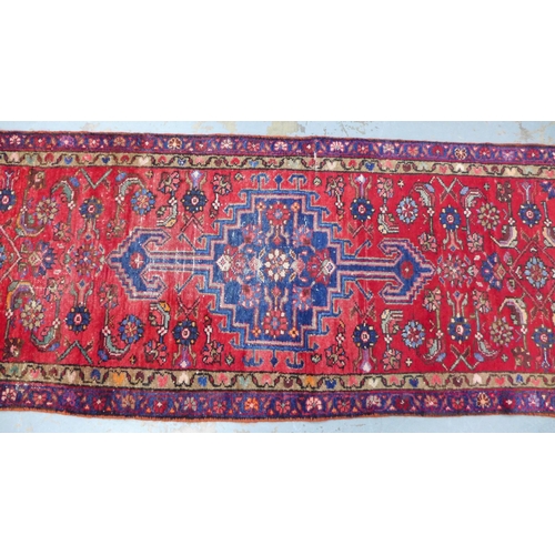 315 - North West Persian runner, red field with a pole medallion and flowerhead borders, 306 x 87cm