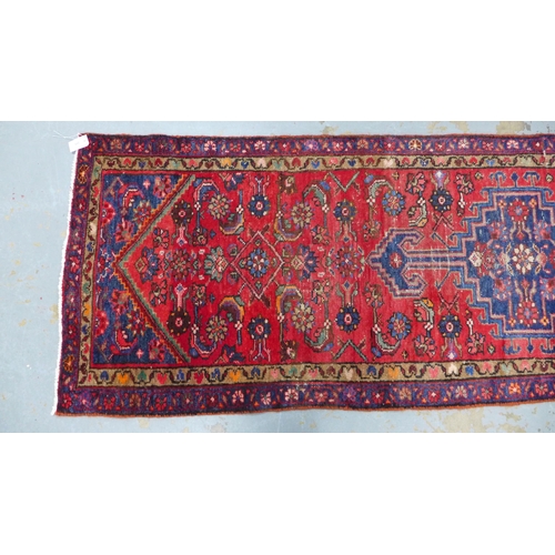 315 - North West Persian runner, red field with a pole medallion and flowerhead borders, 306 x 87cm