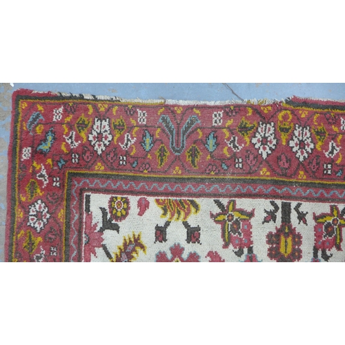 318 - Persian rug, ivory field with flowers and foliage within a red border, 265 x 185cm