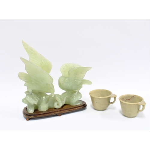 318 - Carved jadeite group of two birds, on a wooden stand, 21cm long, together with two jadeite cups (3)