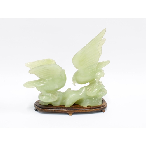 318 - Carved jadeite group of two birds, on a wooden stand, 21cm long, together with two jadeite cups (3)