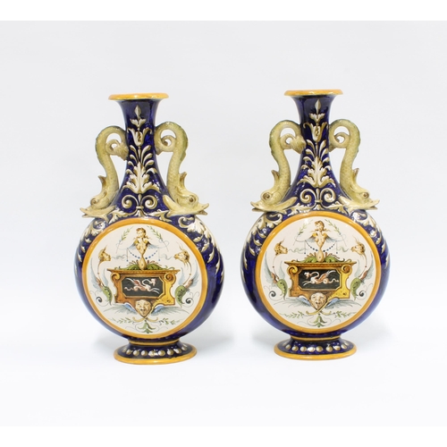 324 - A pair of Italian Ginori majolica vases, with dolphin handles and painted panels,  signed and number... 