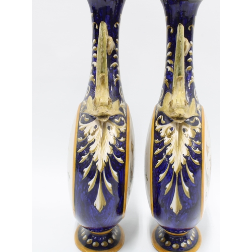 324 - A pair of Italian Ginori majolica vases, with dolphin handles and painted panels,  signed and number... 