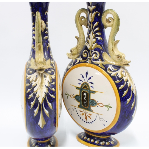 324 - A pair of Italian Ginori majolica vases, with dolphin handles and painted panels,  signed and number... 