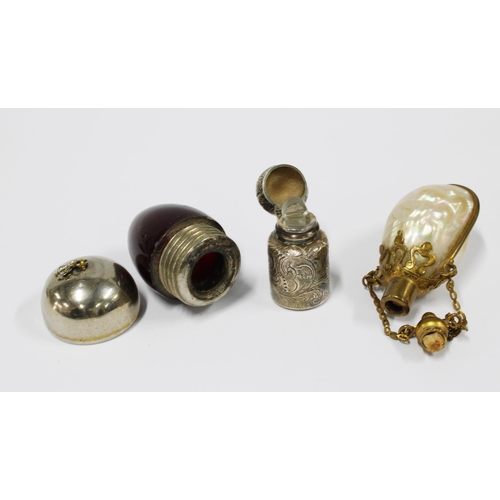 11 - Three scent bottles to include a shell and brass mounted  bottle, cranberry glass and white metal ac... 