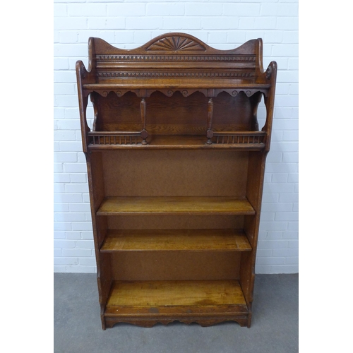 227 - An early 20th century oak open bookcase , the wavy top with dentil and fan carved detail, with quatr... 