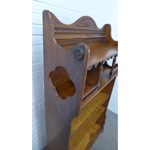 227 - An early 20th century oak open bookcase , the wavy top with dentil and fan carved detail, with quatr... 