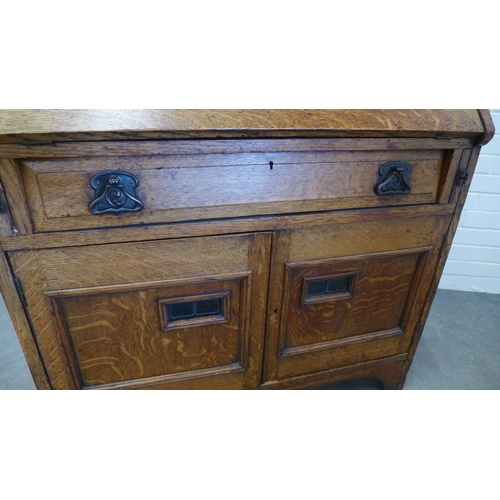 243 - An  early 20th century oak secretaire cabinet, the cornice top above two lead glazed panel doors and... 