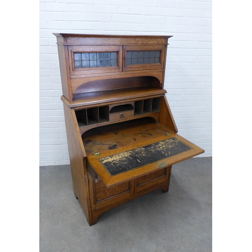 243 - An  early 20th century oak secretaire cabinet, the cornice top above two lead glazed panel doors and... 