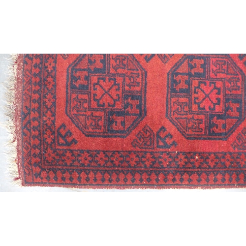 264 - Small Afghan prayer rug with a red field and four medallions. 150 x 57cm.