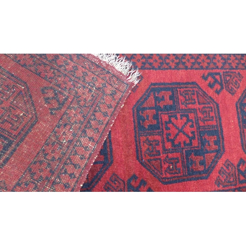 264 - Small Afghan prayer rug with a red field and four medallions. 150 x 57cm.