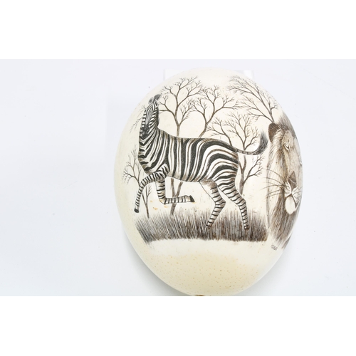 397 - Ostrich egg painted with a lion and a zebra, signed Roger, approx. 18cm high