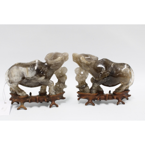 399 - A pair of rock crystal carved water buffalo, modelled standing on associated hardwood bases 20cm lon... 