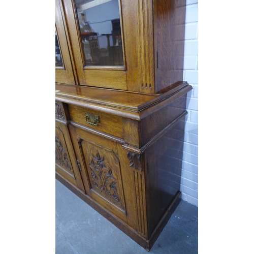 277 - Late 19th / early 20th century oak bookcase cabinet with a broken swan neck top over a  pair of glaz... 