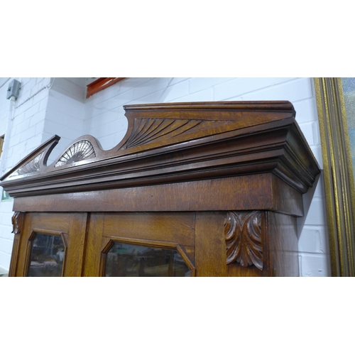 277 - Late 19th / early 20th century oak bookcase cabinet with a broken swan neck top over a  pair of glaz... 