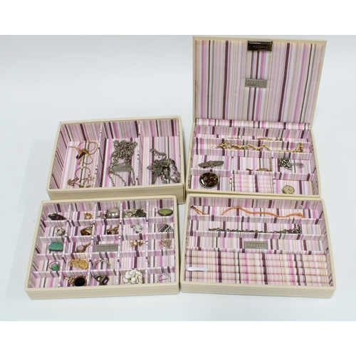 61 - A 'Stackers' cream leather jewellery box, four trays containing a collection of costume jewellery to... 