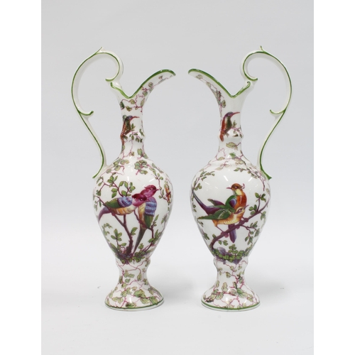 106 - A pair of continental porcelain ewer shaped vases with green rims and shaped handles, white ground w... 