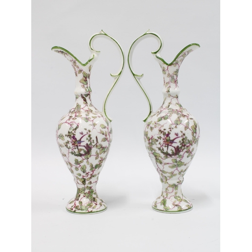 106 - A pair of continental porcelain ewer shaped vases with green rims and shaped handles, white ground w... 