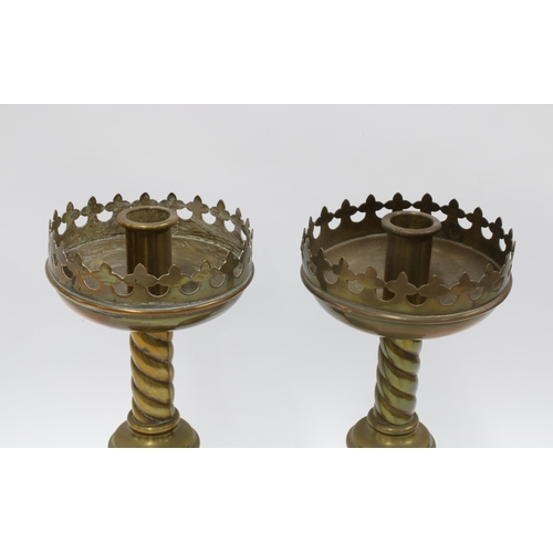 112 - A pair of brass Gothic Revival candlesticks with stylised drip trays, raised on barley twist columns... 