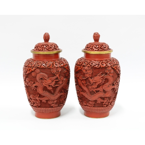 95 - A pair of Chinese red cinnabar vases with covers, carved in high relief with dragons, (2) 19cm.