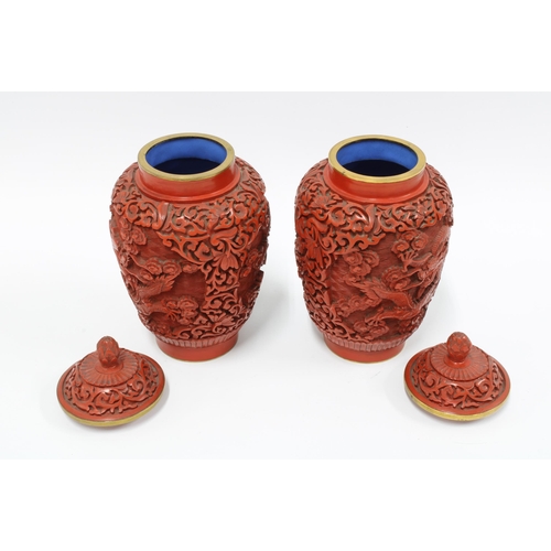 95 - A pair of Chinese red cinnabar vases with covers, carved in high relief with dragons, (2) 19cm.