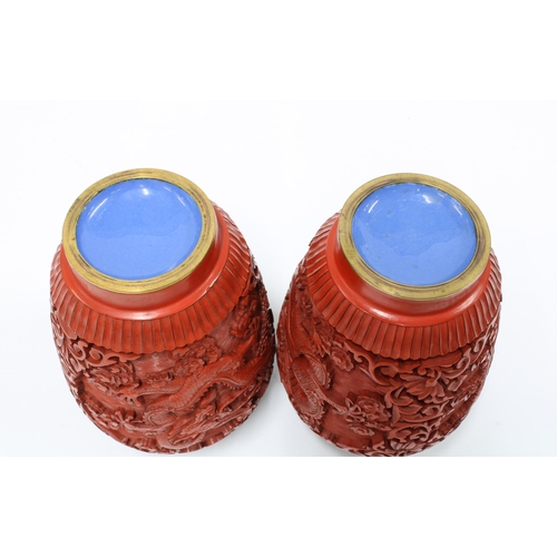 95 - A pair of Chinese red cinnabar vases with covers, carved in high relief with dragons, (2) 19cm.