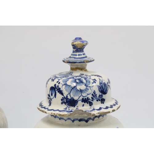 98 - A pair of delft blue and white lidded vases with mixed flowers and wavy bottom border, (2) (some dam... 