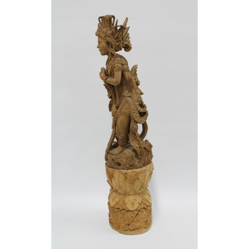 310 - Eastern deity, carved wooden figure on a tall base, possibly Indian (in two parts) 69cm.