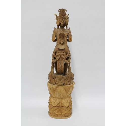 310 - Eastern deity, carved wooden figure on a tall base, possibly Indian (in two parts) 69cm.