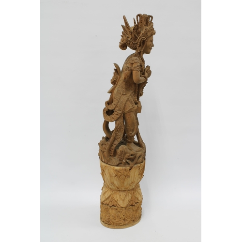 310 - Eastern deity, carved wooden figure on a tall base, possibly Indian (in two parts) 69cm.