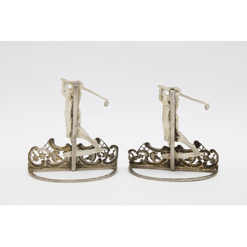 34 - A pair of silver menu card holders by William Comyns,  London 1901, each with a golfer in full swing... 