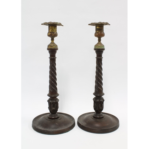 344 - A pair of mahogany candlesticks with brass sconces, spiral stems and circular footrims, (2) 33cm.